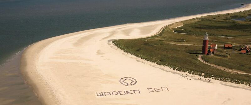 Aerial view on beach next to lighthouse with group of people forming letters 'WADDEN SEA' © Pieter de Vries. Aerial view on beach next to lighthouse with group of people forming letters 'WADDEN SEA' © Pieter de Vries.