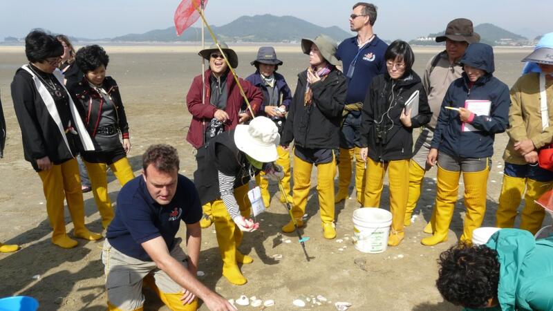 Group of people on exposed mudflats examining the surface. © CWSS.